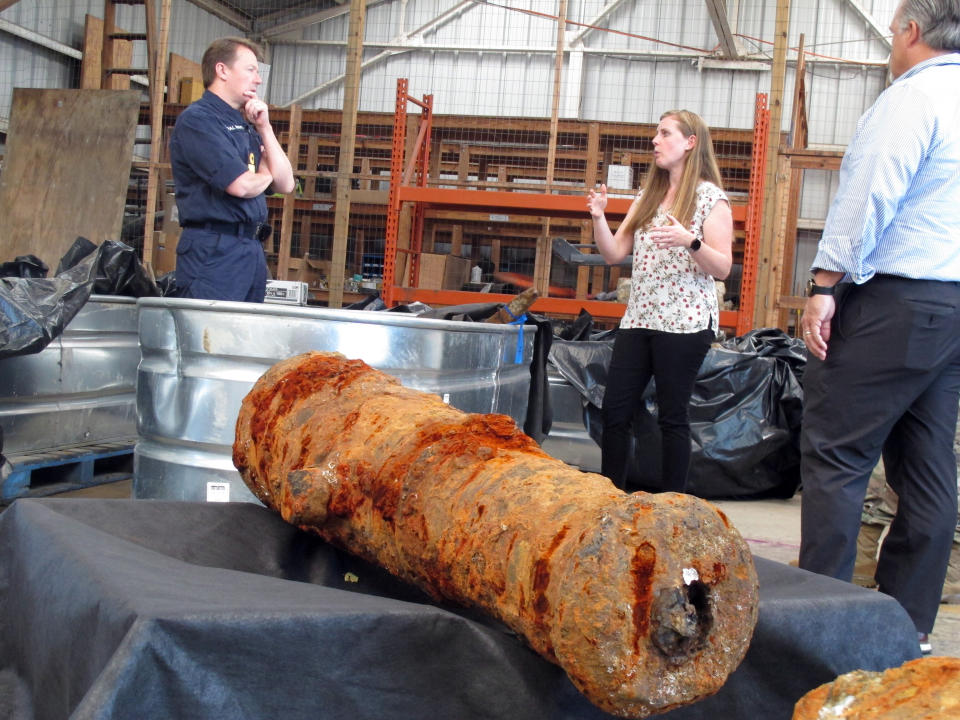 Commodore Philip Nash, left, of the British Royal Navy, gets a briefing from U.S. Army Corps of Engineers archaeologist Andrea Farmer on Thursday, April 28, 2022, in Savannah, Ga., about 19 cannons recovered from the Savannah River, that experts suspect came from one or more British ships scuttled in the river during the American Revolution in 1779. (AP Photo/Russ Bynum)