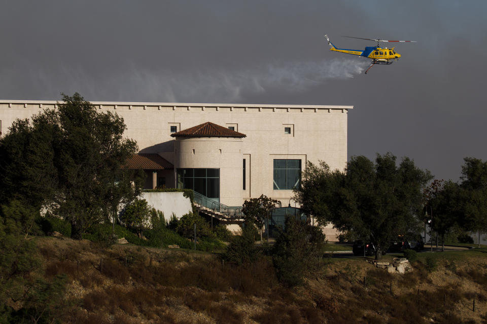 A helicopter drops water to protect the Ronald Reagan Presidential Library during the Easy Fire in Simi Valley, Calif. on Oct. 30, 2019. (Photo: Patrick T. Fallon/Bloomberg via Getty Images)