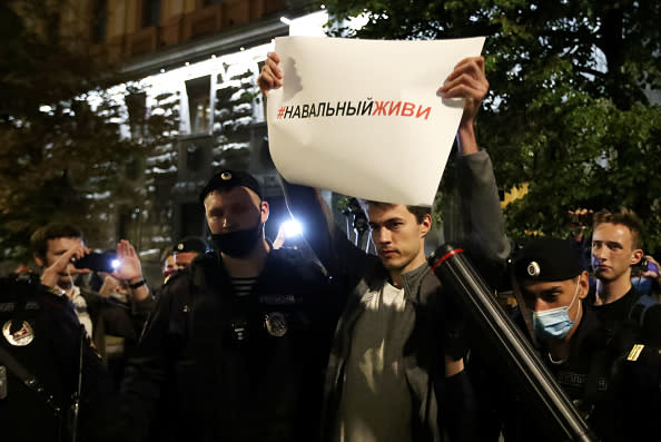 Policemen detain a lone protester with a placard reading "Navalny, Live" outside the Russian Federal Security Service building in Lubyanka Square. 