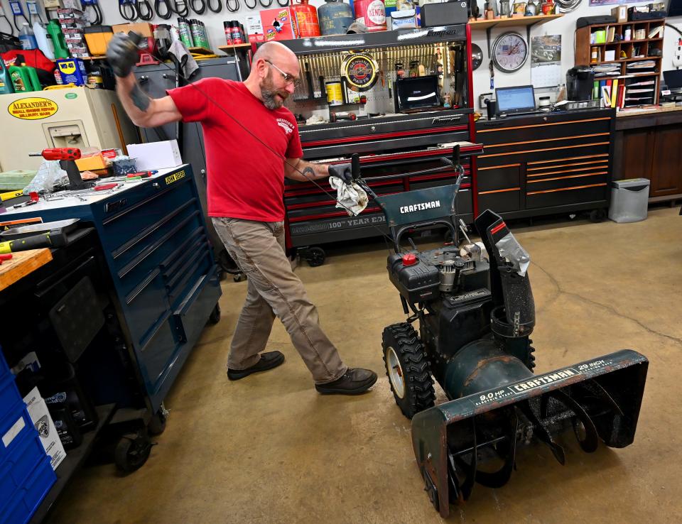 MILLBURY - Dave Alexander of Alexander's Small Engine Repair starts a snowblower as he and his nephew Mark Lizotte work at a brisk pace to get their repair orders done before Saturday's  storm.