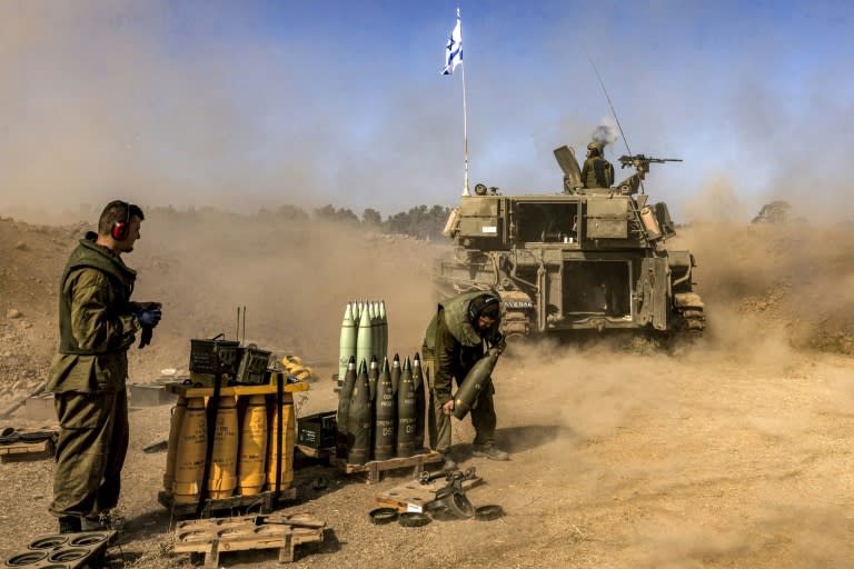 An Israeli army soldier carries rounds from a stockpile towards a stationed self-propelled artillery howitzer firing from a position near the border with the Gaza Strip in southern Israel (MENAHEM KAHANA)