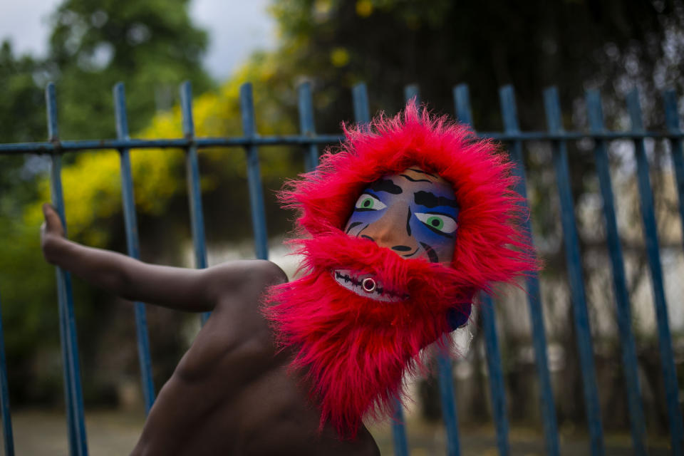 A member of a “bate-bola” or ball hitters group - men who dress up in exuberant, identical, hand-made costumes known as “fantasias” - makes a brief appearance as part of a Carnival tradition despite restrictions due to the new coronavirus pandemic, in Rio de Janeiro, Brazil, Saturday, Feb. 13, 2021. Rio’s city government officially suspended Carnival and warns it will have no tolerance for those who try to celebrate with open street parades or clandestine parties. (AP Photo/Bruna Prado)