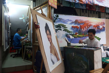 Painters work on their paintings at Dafen Oil Painting Village in Shenzhen, Guangdong province, China December 5, 2018. REUTERS/Thomas Suen/Files