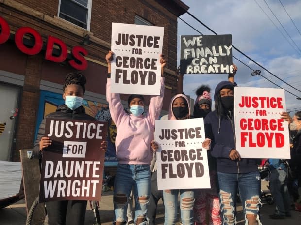 People in George Floyd Square in Minneapolis hold signs calling for justice for Floyd and Daunte Wright, who were killed in separate encounters with police. On Tuesday, former Minneapolis police officer Derek Chauvin was convicted of murder and manslaughter in Floyd's death. (Carly Thomas/CBC - image credit)