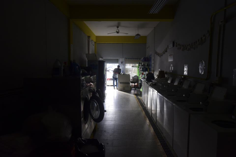 Laundromat owner Jesus Vazquez pauses before closing his shop to comply with the government's curfew aimed at curbing the spread of the new coronavirus, which is shuttering all non-essential businesses for two weeks in San Juan, Puerto Rico, Friday, March 20, 2020. (AP Photo/Carlos Giusti)