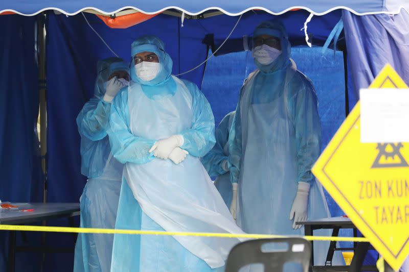 Health workers in protective suits wait for patients in a tent erected to test for coronavirus at a clinic, in Kuala Lumpur