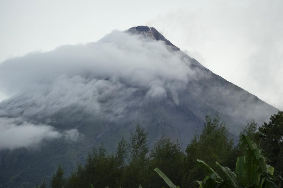 The summit of the Mayon Volcano is seen from Bonga, Albay province, northeastern Philippines, Saturday, June 10, 2023. Philippine Institute of Volcanology and Seismology reports a new summit lava dome in the Mayon volcano crater emerged as its pre-existing one has been pushed out in increments that formed rockfall in the first week of June 2023. Monsoon rains that could be unleashed by an offshore typhoon were complicating worries of villagers threatened by a restive Philippine volcano that has forced thousands of people to flee from their homes.(AP Photo/Aaron Favila)