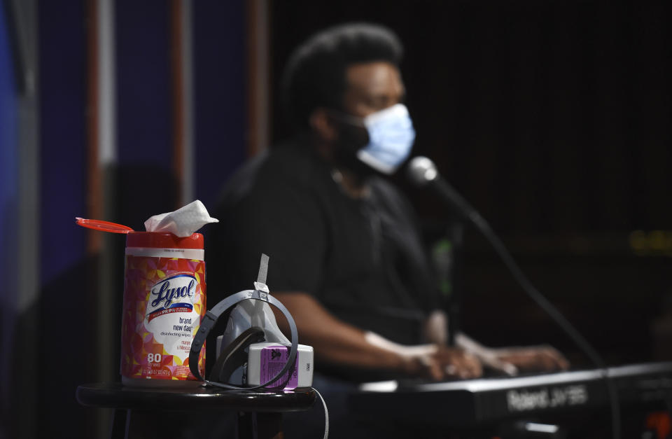 In this April 20, 2020, photo, a bottle of Lysol disinfectant wipes sits on a table onstage as comedian Craig Robinson performs during a "Laughter is Healing" stand-up comedy livestream event at the Laugh Factory in Los Angeles. With comedy clubs closed and concert tours put on hold, comics like Robinson, Tiffany Haddish, Will C and others are keeping the jokes flowing on webcasts and Zoom calls even without the promise of a payday, because they say the laughs are needed now more than ever. (AP Photo/Chris Pizzello)