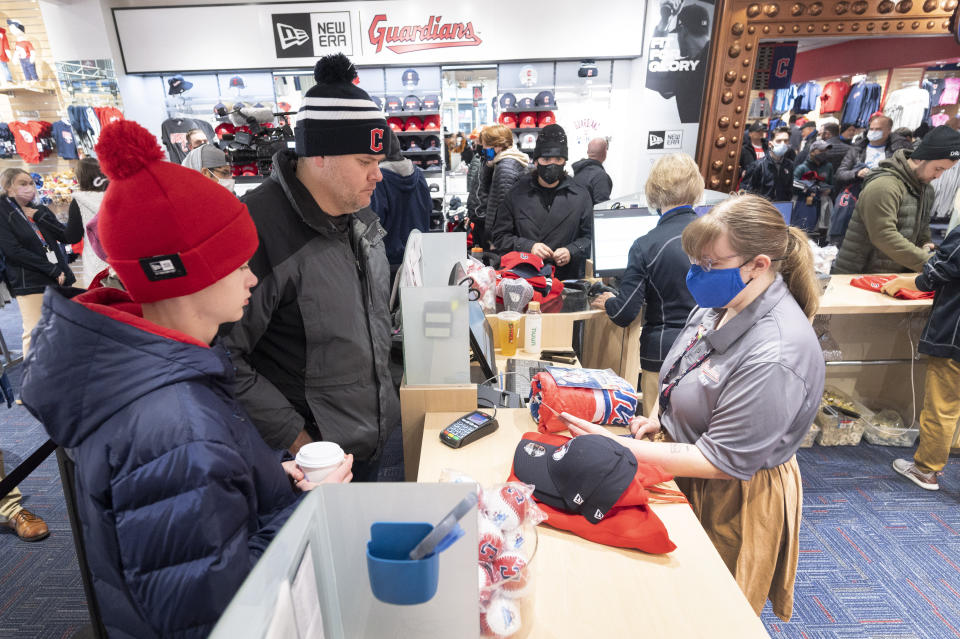 Lucas Foote, left, and Greg Foote, center, check out at the opening of the Cleveland Guardians team store in Cleveland, Friday, Nov. 19, 2021, in Cleveland. It's Day One for the Guardians, who will put caps, jerseys and other merchandise on sale to the public for the first time since dropping the name Indians, the franchise's identity since 1915. (AP Photo/Ken Blaze)