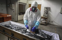 An employee takes the fingerprints of a woman who died from the new coronavirus before her remains are cremated at La Recoleta crematorium in Santiago, Chile, Saturday, June 27, 2020. The Ministry of Health reported on Saturday the highest number of deaths in Chile since the start of the pandemic. (AP Photo/Esteban Felix)