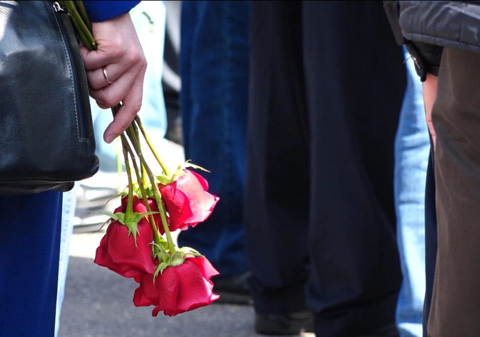 In this grab taken from a footage provided by the Russian State Atomic Energy Corporation ROSATOM press service, a woman holds roses as she and other people gather for the funerals of five Russian nuclear engineers killed by a rocket explosion in Sarov, the closed city, located 370 kilometers (230 miles) east of Moscow, which has served as a base for Russia's nuclear weapons program since the late 1940s, Russia, Monday, Aug. 12, 2019. Russia's Rosatom state nuclear concern said Thursday's explosion at a military testing range in northwestern Russia occurred while the engineers were testing a "nuclear isotope power source" for a rocket engine, a tragedy that fueled radiation fears and raised new questions about a secretive weapons program (Russian State Atomic Energy Corporation ROSATOM via AP)