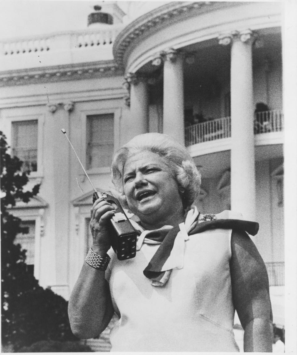 Liz Carpenter working a walkie-talkie in front of the White House. Carpenter did not just handle the press for Lady Bird Johnson, she minutely organized public events and acted as a link between the staff members of the first lady and the president.