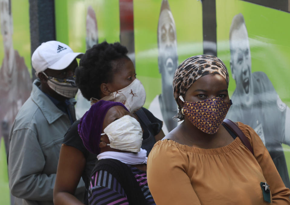 People wearing face masks queue at a South African Social Security Agency (SASSA) to collect their government grant in Cape Town South Africa, Monday, May 11, 2020. South Africa's Western Cape province, which includes the city of Cape Town, has emerged as the country's coronavirus hotspot, accounting for more than half of the nation's confirmed cases, which have gone above 10,000.(AP Photo/Nardus Engelbrecht)