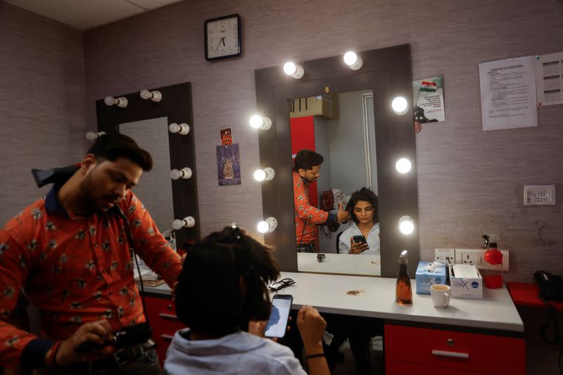 Neha Singh Rathore, 27, a folk singer and social media content creator, looks at her phone inside the make-up studio of a national television news network as she gets ready for a debate, in Noida