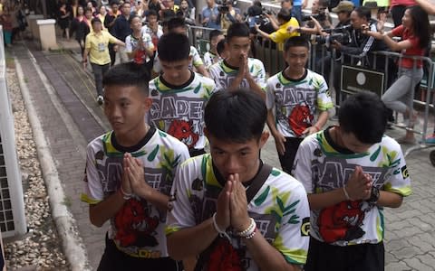 The boys clasp their hands together as a token of thanks to the gathered media - Credit: AFP