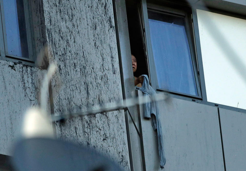 <p>A person peers out of a window from a building on fire in London, Wednesday, June 14, 2017. Metropolitan Police in London say they’re continuing to evacuate people from a massive apartment fire in west London. The fire has been burning for more than three hours and stretches from the second to the 27th floor of the building. (Matt Dunham/AP) </p>