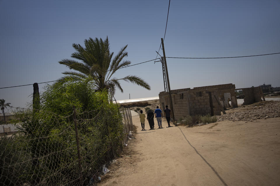 The Zorob family walk away from the site of their destroyed home, heading back to their single-room nylon-covered hut in Khan Younis, southern Gaza Strip, Monday, Aug. 28, 2023. The Gaza Strip's displaced families await the completion of nearly 1,400 Egyptian-sponsored housing units, a project mired in political disputes between the Palestinian Authority and Gaza's Hamas-run government. The Zorob family, like thousands of others, remains caught in the crossfire, living in makeshift conditions while nearly completed apartments stand empty.(AP Photo/Fatima Shbair)