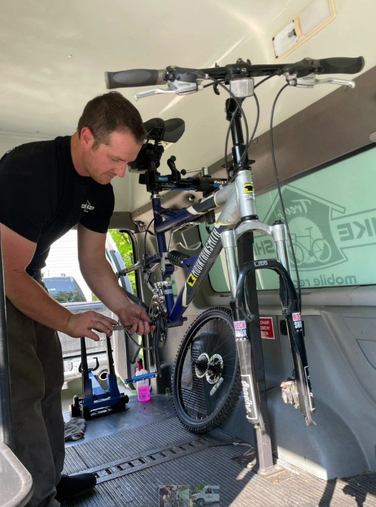 Trevor Schick repairing a bike inside his mobile bike shed.