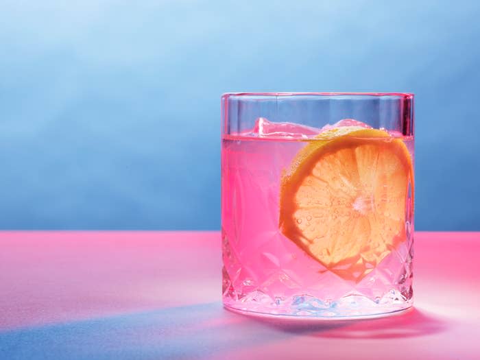 Glass of water with a slice of lemon on a reflective surface