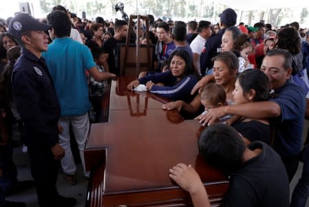Relatives of a police officer, who was killed along other fellow police officers during an ambush by suspected cartel hitmen, react during an homage organised by the state government, in Morelia