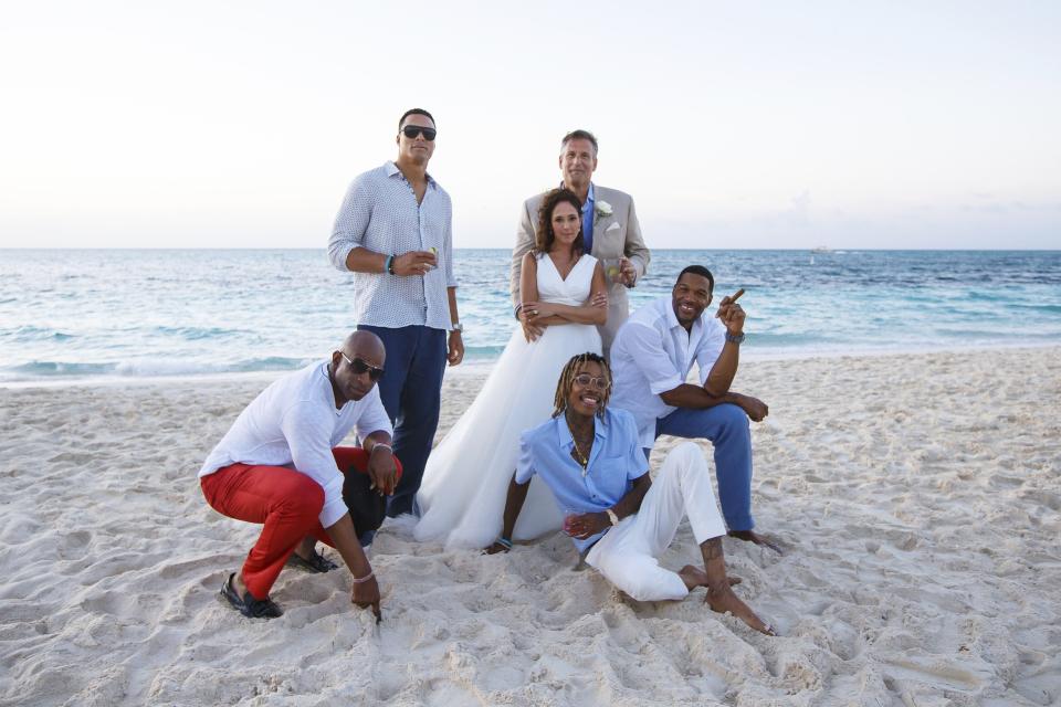 This photo provided by Constance Schwartz-Morini shows, from left, Deion Sanders, Tony Gonzalez, bride and groom Mike Morini and Constance Schwartz-Morini, Wiz Khalifa and Michael Strahan at their wedding in Turks and Caicos, June 19, 2015. Schwartz-Morini is Coach Prime's trusted advisor/business associate/friend/guardian, one who's built a resume working with the likes of Hall of Famer Michael Strahan, her business co-founder turned “Good Morning America” host, and rapper Wiz Khalifa. (Brilliant Studios/Constance Schwartz-Morini via AP)