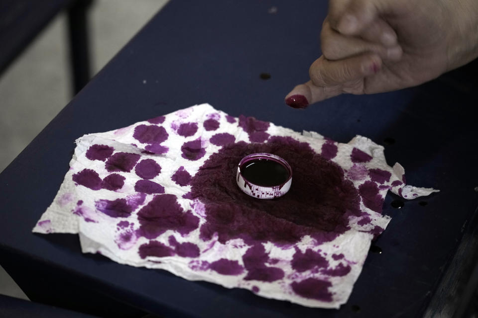 A voter dips her finger in ink after casting her vote for the presidential elections at a polling station, in Cairo, Egypt, Sunday, Dec. 10, 2023. Egyptians began voting Sunday in a presidential election in which President Abdel Fattah el-Sissi, who faces no serious challenger, is certain to win another term, keeping him in power until 2030. (AP Photo/Amr Nabil)