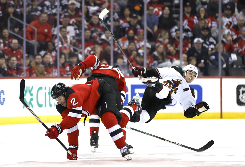 New Jersey Devils defenseman Brendan Smith (2) and Arizona Coyotes right wing Clayton Keller (9) collide during the second period of an NHL hockey game Friday, Oct. 13, 2023, in Newark, N.J. (AP Photo/Noah K. Murray)