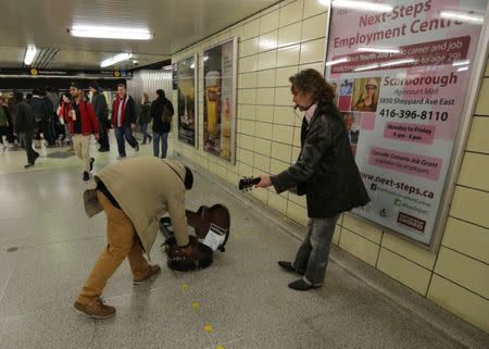 Honduran migrant Raul Contreras, who is seeking refugee status in Canada, gives money to a subway entertainer while travelling to a church service held in Spanish in Toronto, Ontario, Canada April 8, 2017. REUTERS/Chris Helgren