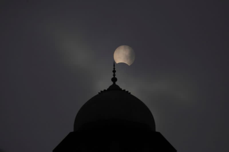 A general view of a mosque with a partial solar eclipse in the background in Lahore