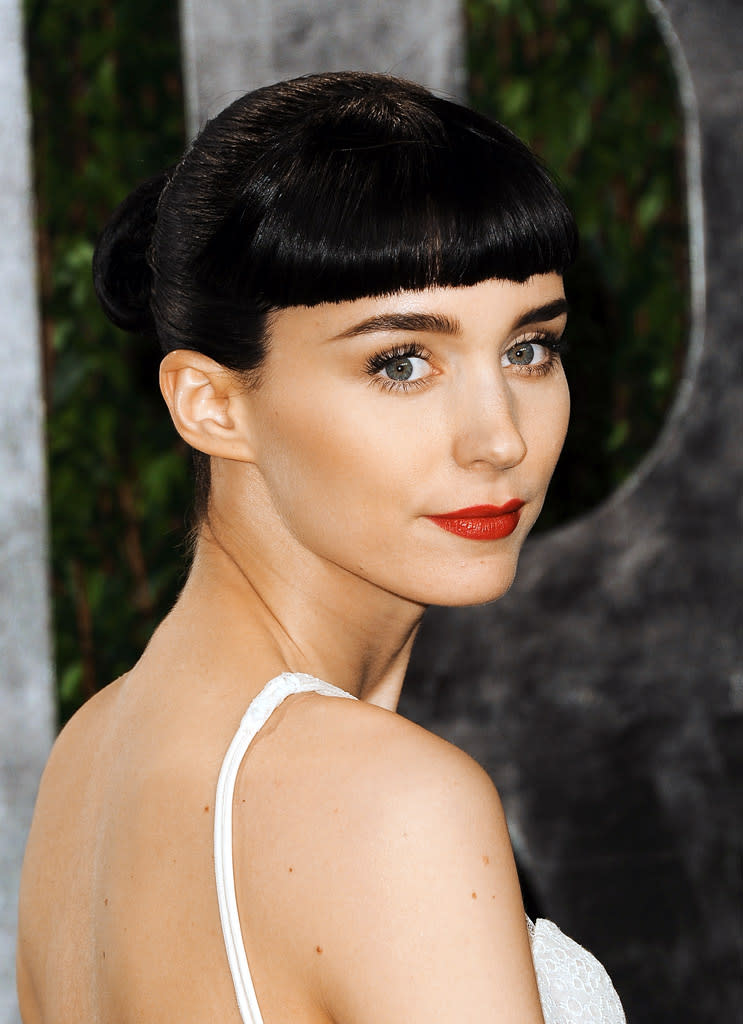 “The Girl With the Dragon Tattoo” actress Rooney Mara – who we’re used to seeing with dramatic ‘dos – sported yet another one when she hit the red carpet at the Oscars severely blunt bangs and pulled back dark tresses on Oscar night, the perfect contrast to her white Givenchy Couture gown.