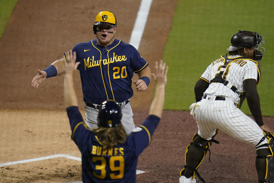 Milwaukee Brewers' Daniel Vogelbach (20) celebrates with teammate Corbin Burnes (39) after they both scored off a two-RBI double by Travis Shaw as San Diego Padres catcher Luis Campusano waits for the throw, right, during the third inning of a baseball game Tuesday, April 20, 2021, in San Diego. (AP Photo/Gregory Bull)