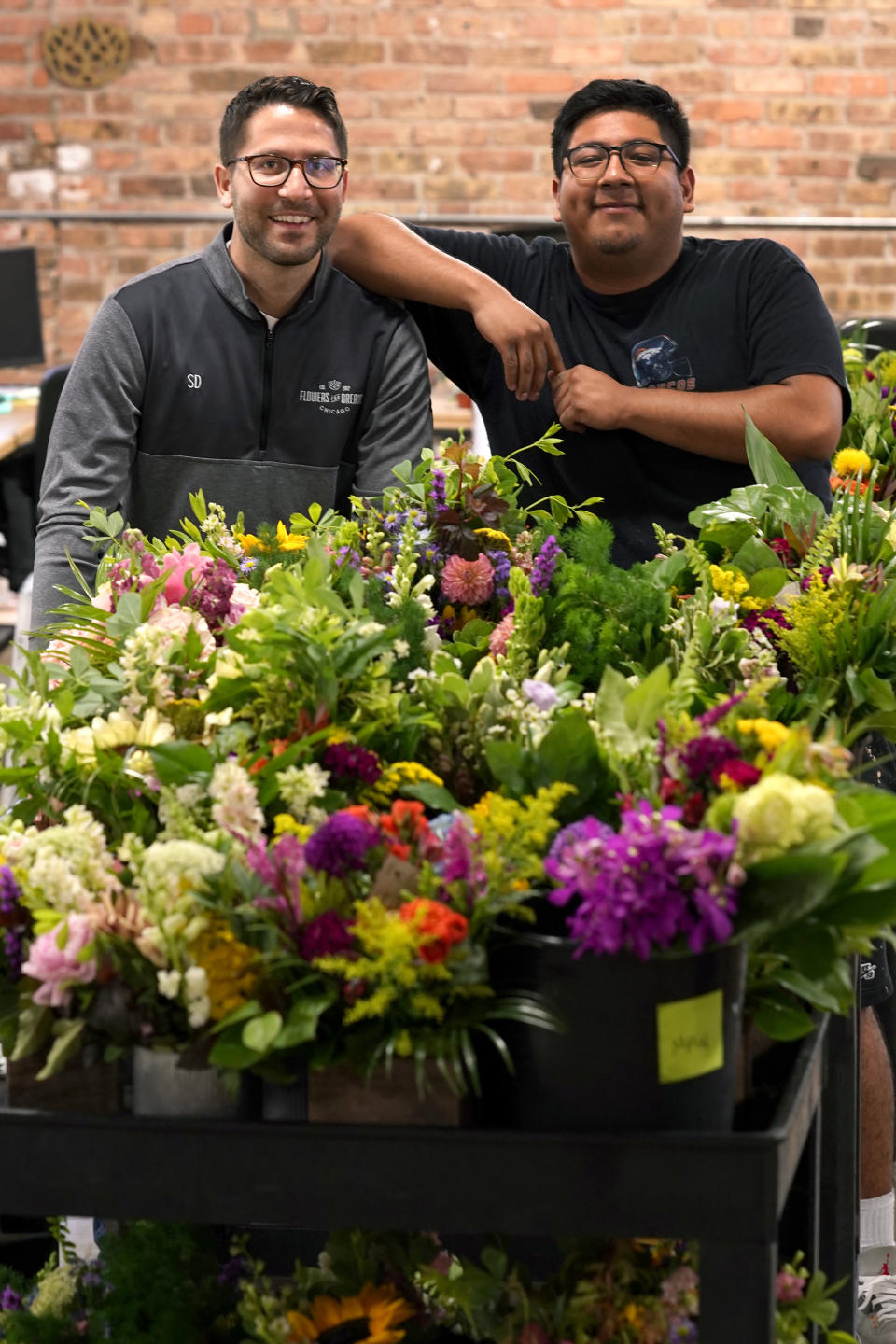 Steven Dyme, owner of Flowers for Dreams, poses with employee Kevin Cervantes for a portrait at the company's warehouse Friday, July 23, 2021, in Chicago. Dyme says the $15 minimum made it much easier to staff up when the economy reopened this spring and demand for flowers, particularly for weddings, soared. The company has four locations, including its headquarters in Chicago, one in Milwaukee, and two in Detroit. (AP Photo/Charles Rex Arbogast)