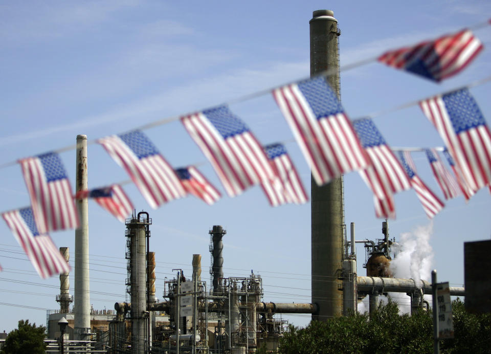 FILE - In this April 30, 2008 file photo, American flags are seen near the Shell refinery, in Martinez, Calif. On Weds., Nov. 14, 2012, California’s largest greenhouse gas emitters will for the first time begin buying permits in a landmark “cap-and-trade” system meant to control emissions of heat-trapping gases and spur investment in clean technologies. The program is a key part of California’s 2006 climate-change law, AB32, a suite of regulations that dictate standards for cleaner-burning fuels, more efficient automobiles and increased use of renewable energy. (AP Photo/Ben Margot, File)