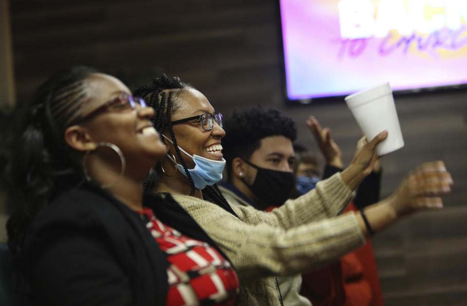 Sisters Shawnetta Lane, left, and Angenetta Lane, center, smile as they listen to Frederick Brown, pastor of Faith Center Church in Bluefield, W.Va., give his first in-person sermon in two months on Sunday, Jan. 24, 2021. (AP Photo/Jessie Wardarski)