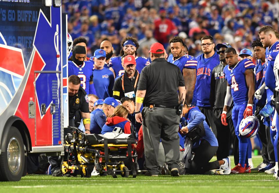 Buffalo Bills platers and coaches stand around medical personnel attending to cornerback Dane Jackson.