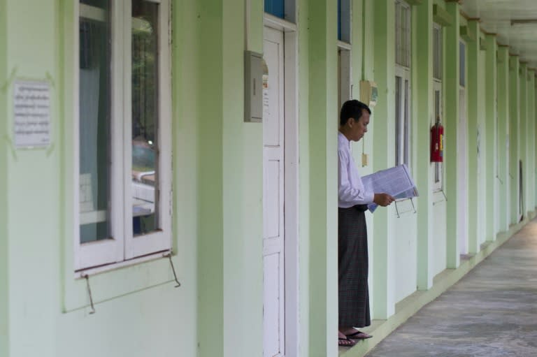 Phyo Min Thein, a Lower House MP for the National League for Democracy reads a newspaper in the doorway of his lodgings in Naypyidaw on August 24, 2015