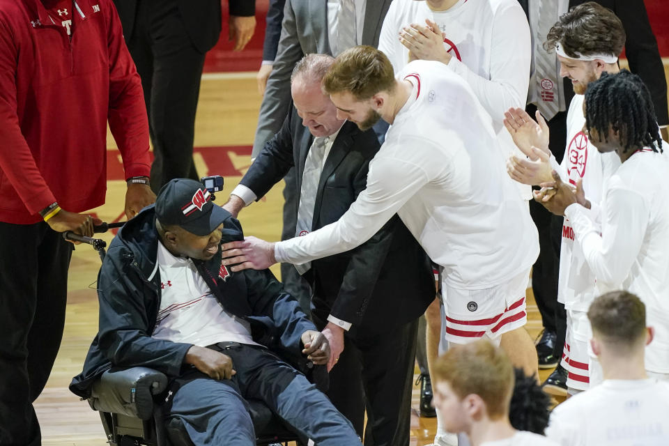 Former Wisconsin player and assistant coach Howard Moore is greeted by the Wisconsin team Saturday, March 2, 2024, in Madison, Wis., in in his first public appearance at the Kohl Center since a 2019 car wreck killed his wife and daughter and left him with serious injuries. (AP Photo/Andy Manis)