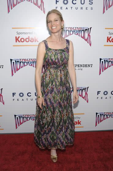 Bridget Fonda in a green and purple patterned dress posing on a red carpet