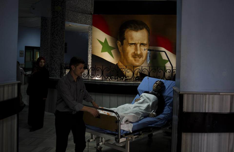 A patient is wheeled through the Damascus General Hospital past a portrait of the President Bashar Assad in Damascus, Syria, Sunday, May 4, 2014. An official with Syria's Supreme constitutional Court said Assad and two others will be candidates in coming June presidential elections. (AP Photo/Dusan Vranic)