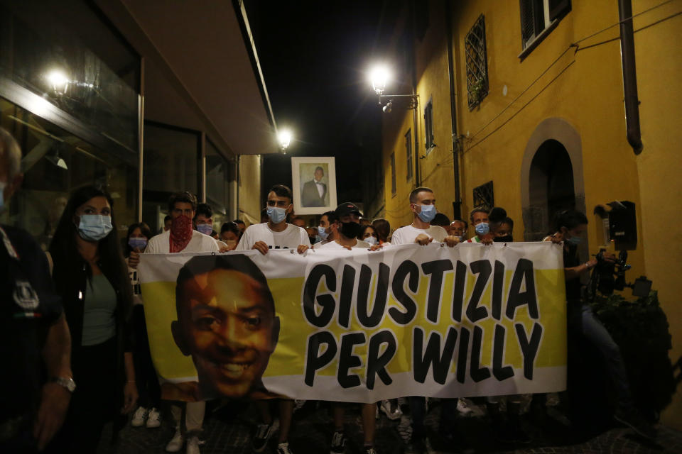 People walk holding a banner reading "Justice for WIlly" during a torch light procession in memory of Willy Monteiro Duarte, in Paliano, Italy, Wednesday, Sept. 9, 2020. Hundreds of people have walked in a funeral procession honoring a young Black man whose brutal beating death during a fight has convulsed Italy and drawn condemnation from the highest levels of the government. Premier Giuseppe Conte and Italy’s interior minister attended the funeral Saturday for 21-year-old Willy Monteiro Duarte, who was killed in the early hours of Sept. 6 in Colleferro, a city on the outskirts of Rome. (Cecilia Fabiano/LaPresse via AP)