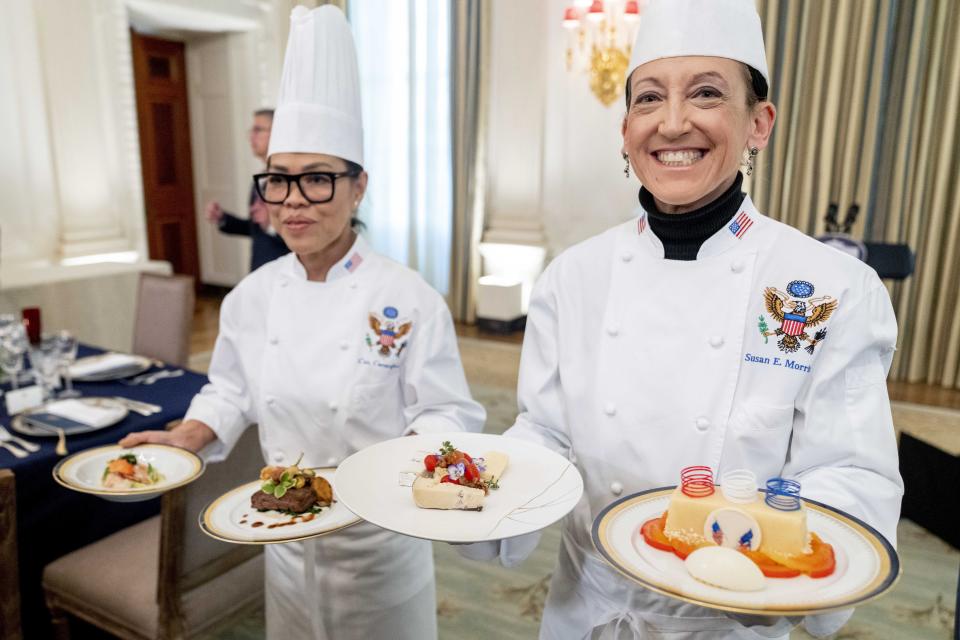 White House executive chef Cris Comerford, left, and White House executive pastry chef Susie Morrison, right, hold dishes during a media preview for the State Dinner with President Joe Biden and French President Emmanuel Macron in the State Dining Room of the White House in Washington, Wednesday, Nov. 30, 2022. The dinner will include a butter poached Maine lobster, beef with shallot marmalade, American artisanal cheeses, and an orange chiffon cake for desert. (AP Photo/Andrew Harnik)