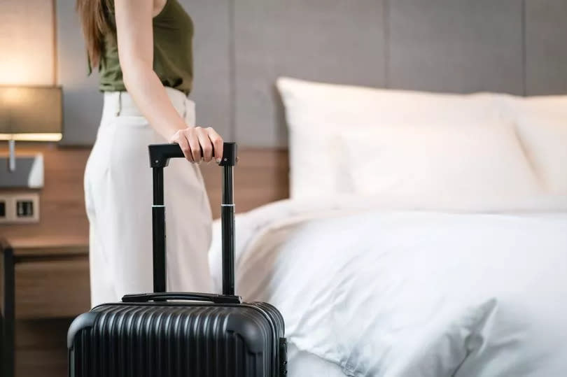 Close up a woman with suitcase standing in hotel room. travel and vacations concept.