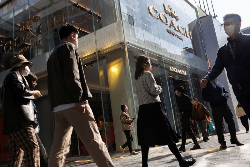 People walk past a store of the Coach luxury fashion retailer in a shopping district in Beijing