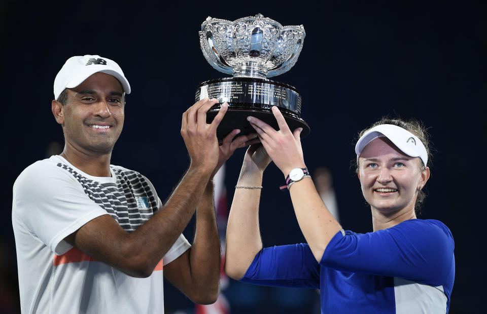 Rajeev Ram of the US and Barbora Krejcikova of the Czech Republic hold their trophy after defeating Australia's Samantha Stosur and Matthew Ebden in the mixed doubles final at the Australian Open tennis championship in Melbourne, Australia, Saturday, Feb. 20, 2021.(AP Photo/Andy Brownbill)