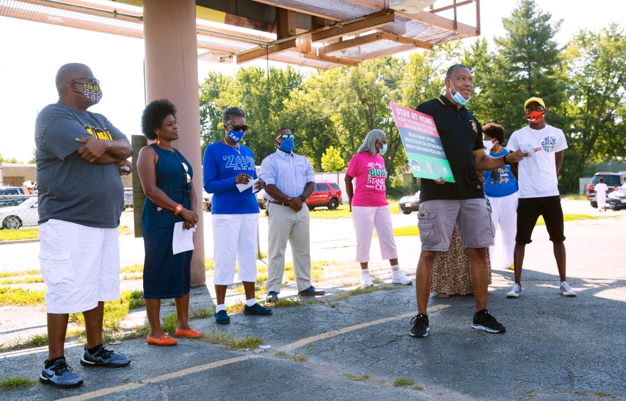 Marc E. Bell holds a sign promoting hand washing, social distancing and mask wearing as he addresses a crowd gathered for the unveiling of one of two new billboards bearing the same message on East Cook Street in Illinois on Saturday, Aug. 22, 2020. The billboards are part of a larger collective effort by a number of organizations, including seven Black Greek organizations, to provide support and promote education about COVID-19.