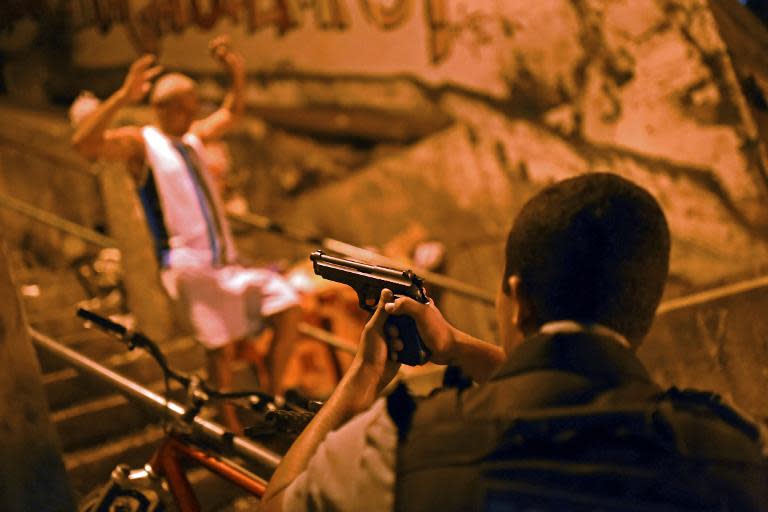 A Brazilian Police Special Forces member aims at a man walking past with his hands up during a violent protest in a favela near Copacabana in Rio de Janeiro, Brazil on April 22, 2014