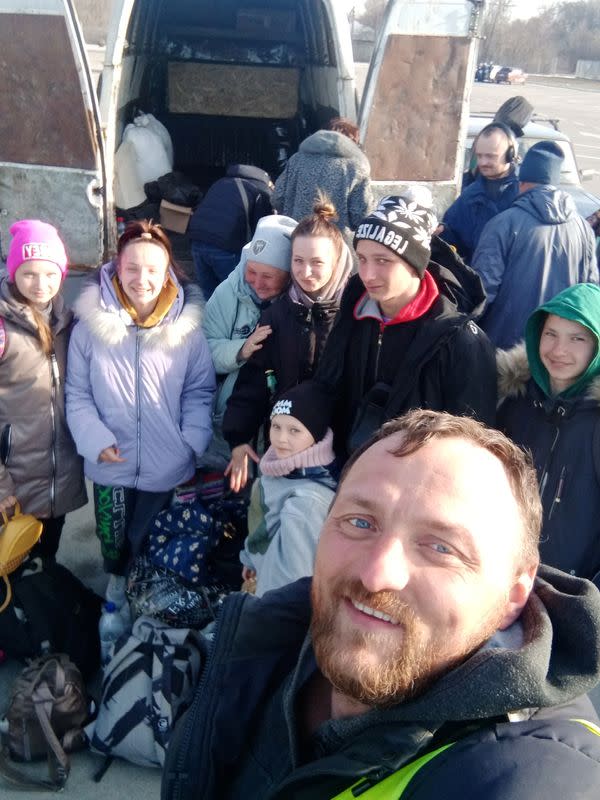 Mykhailo Puryshev poses for a selfie photo with people fleeing Russia's invasion of Ukraine, in Zaporizhzhia