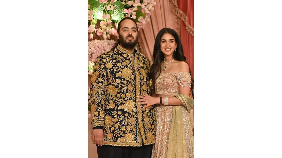 Anant Ambani in a gold jacket with Radhika Merchant in an off the shoulder top