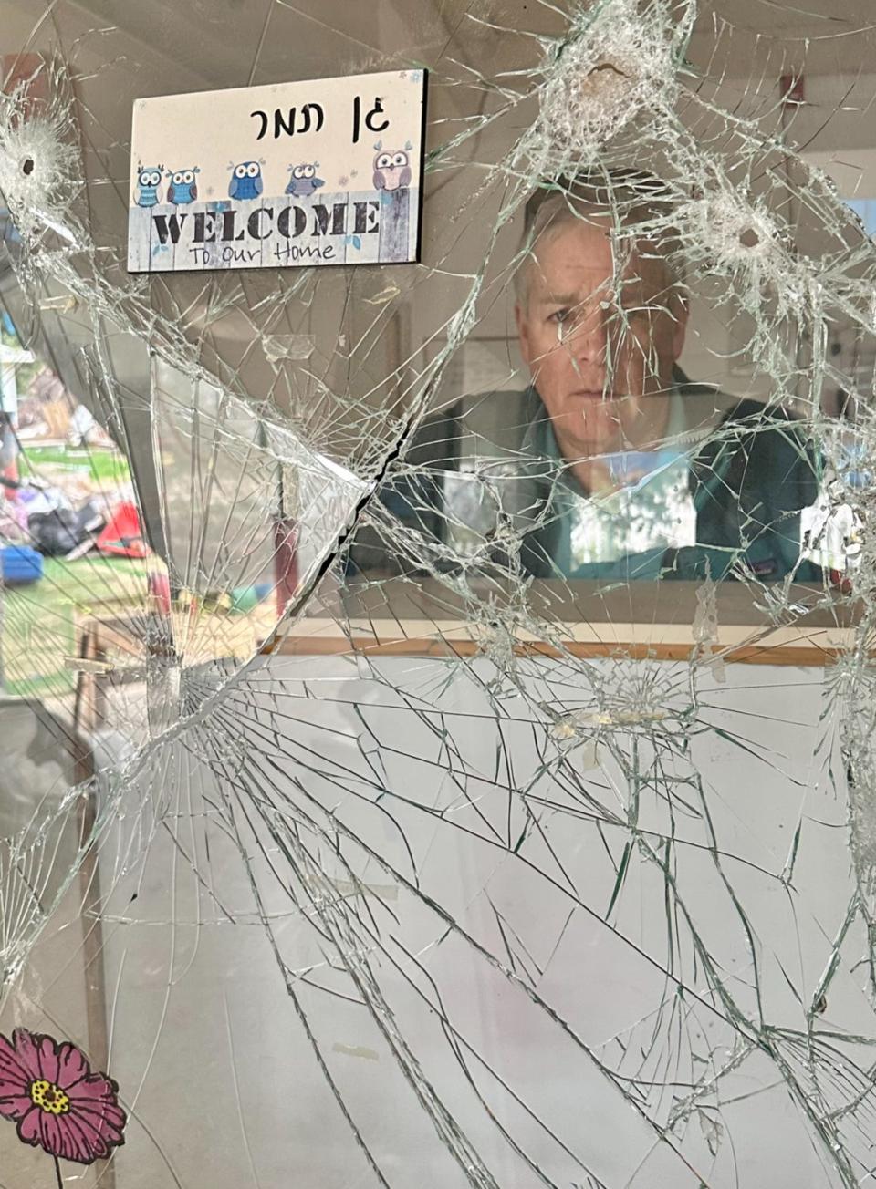 Mark Patinkin looks through a shattered window with a bullet hole in the kindergarten area of Kibbutz Be'eri.