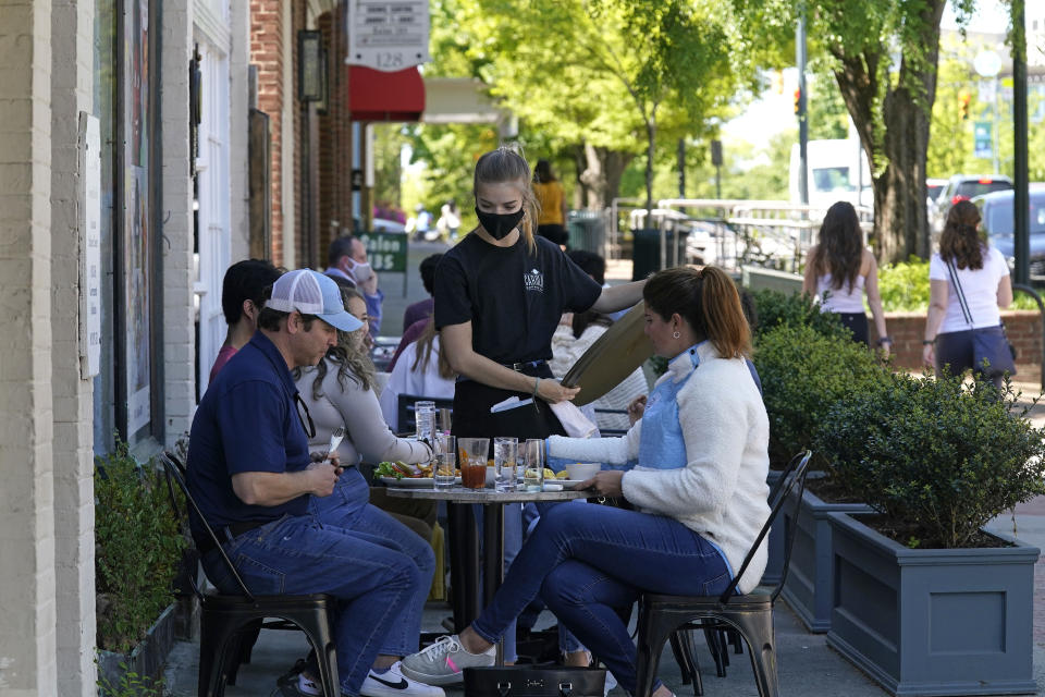 Patrons are assisted while dining along a sidewalk on Franklin Street in Chapel Hill, N.C., Friday, April 16, 2021. As consumers increasingly venture away from home, demand has begun to shift away from manufactured goods and toward services, from airline fares to restaurant meals, triggering inflation in those areas. (AP Photo/Gerry Broome)